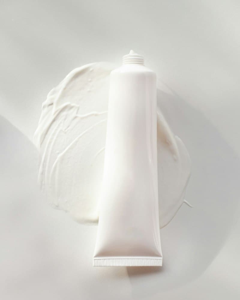 A plain white tube beside a swirl of white cream