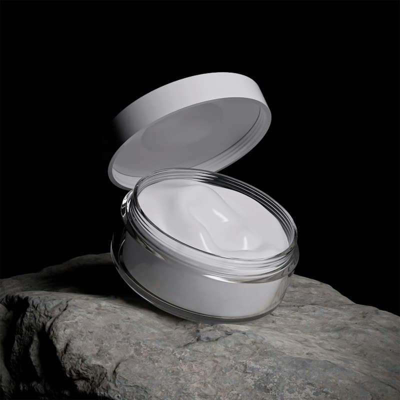 An open jar of white cream on a dark stone against a black background