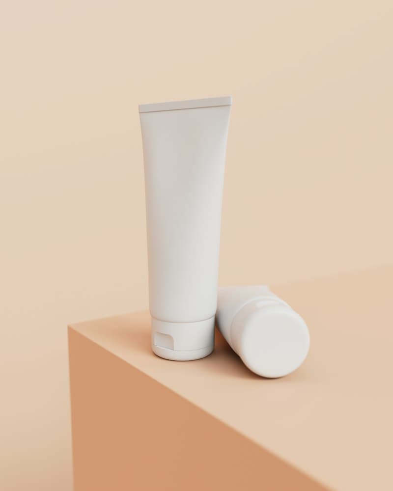 Two plain white tubes on a peach-coloured block